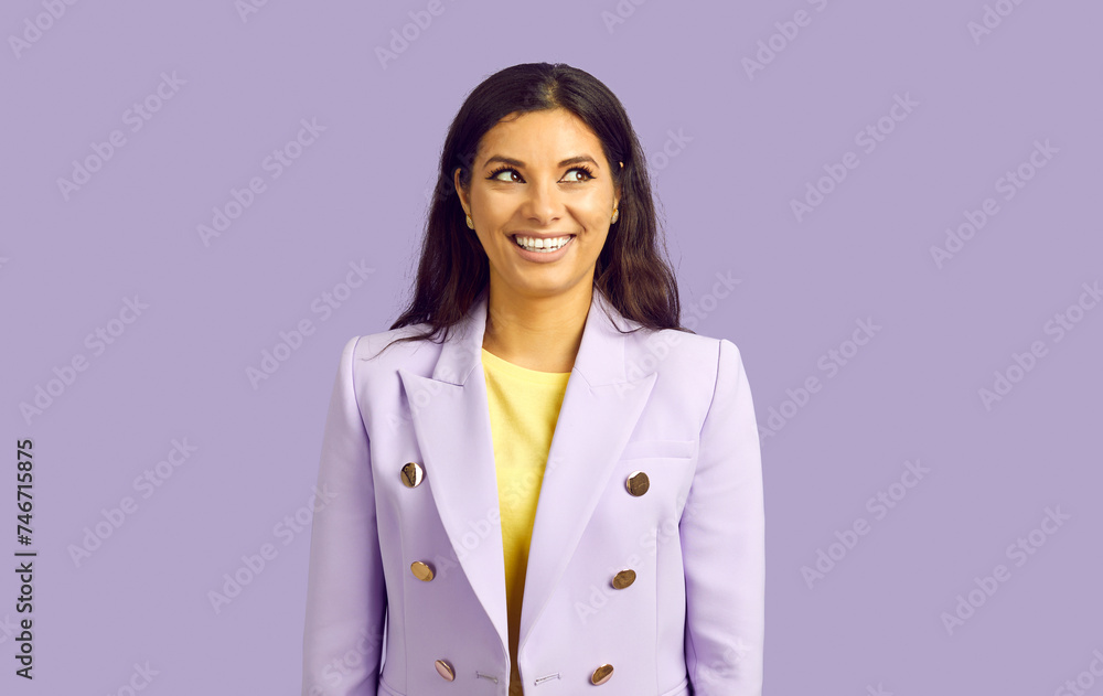 Portrait of beautiful dreamy businesswoman or manager looking at side with copy space, smiling happily, posing isolated over purple color background. Brunette female in suit stands thinking Portrait of beautiful dreamy businesswoman or manager looking at side with copy space, smiling happily, posing isolated over purple color background. Brunette female in suit stands thinking