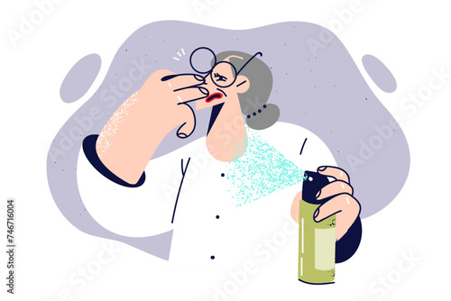 Elderly woman uses air freshener to get rid of harmful smell in apartment, and covers nose