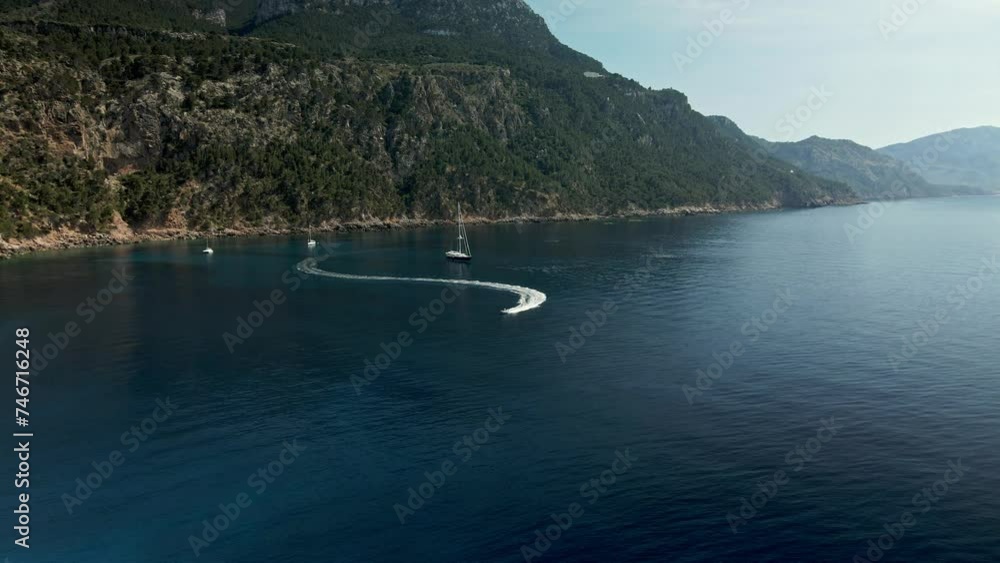 Spanish coast of Mallorca island, people on vacation driving jetskis in the blue sea bay under the summer sun