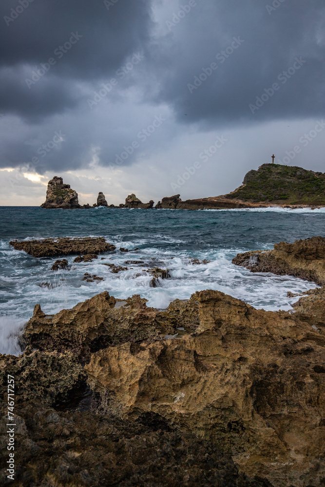 Stony coast with sharp rock formations on a bay in the sea. rainy sunrise, dramatic mood. Pointe des Chateau overlooking Pointes des colibris on Grande Terre, Guadeloupe, French Antilles, Caribbean