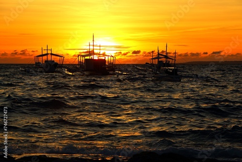 Ship on the tropical sea with waves, under the vivid orange sunset. Evening sun and waves on the ocean, anchoring boats. Travel picture, ships on the sea. © blue-sea.cz