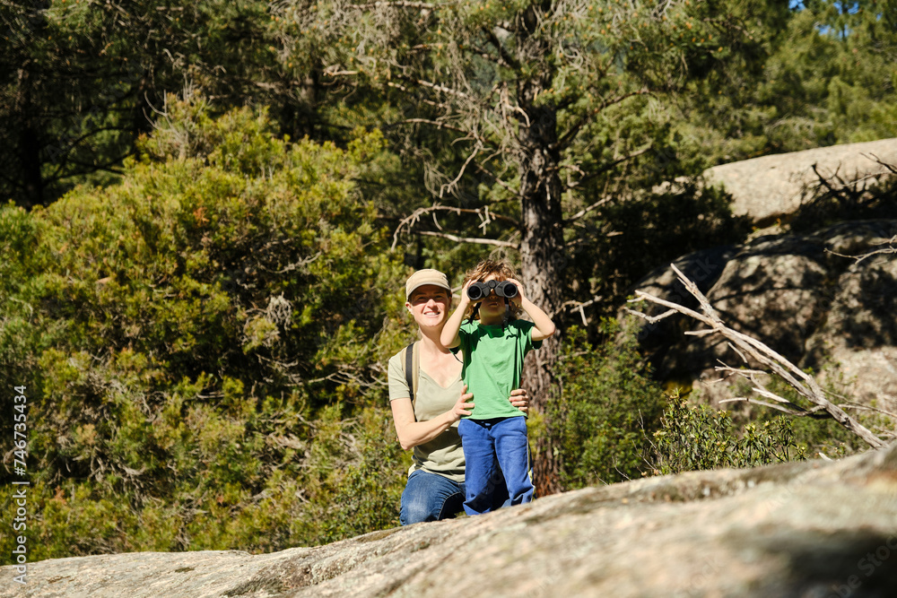 Mother and son in woods with binoculars.