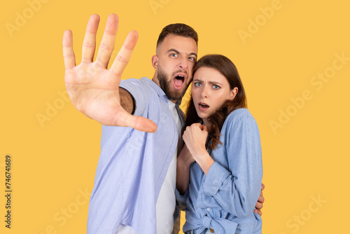 Frightened young european couple gesturing stop to camera photo