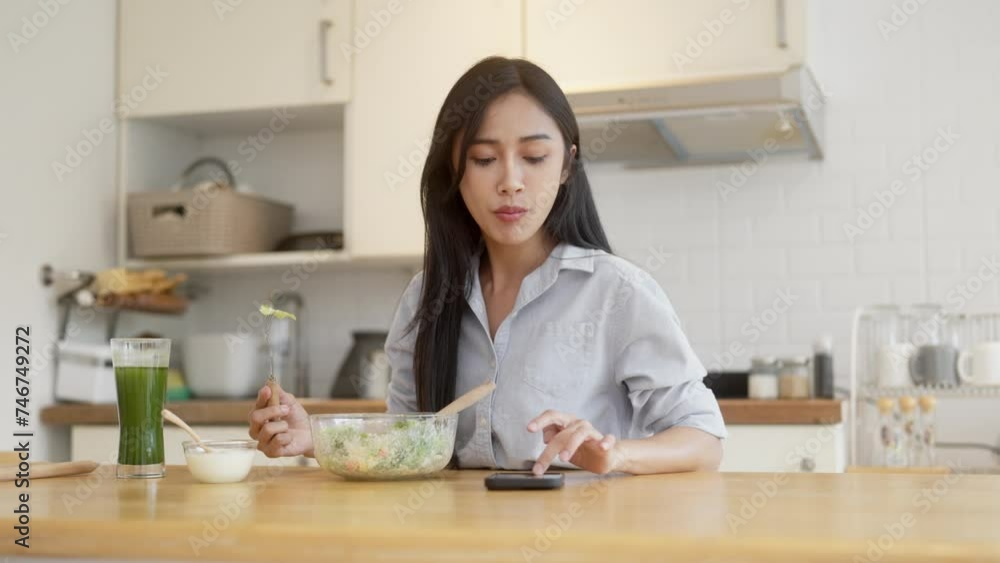 Young asian woman using smartphone while eating on counter table Young asian woman using smartphone while eating on counter table