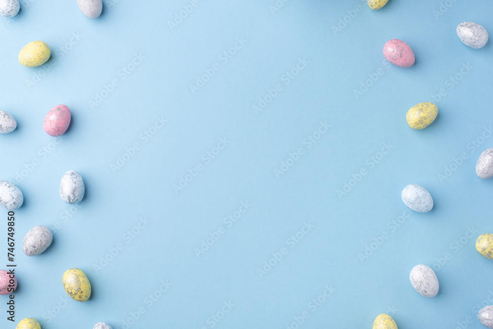 Festive Easter background. Multicoloured Easter eggs on a blue table. Card with a place for text. Top view. Festive Easter background. Multicoloured Easter eggs on a blue table. Card with a place for text. Top view.