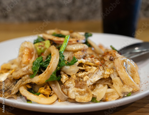 A delicious plate of stir-fried noodles with fresh seafood, vegetables, and a sprinkle of spices.