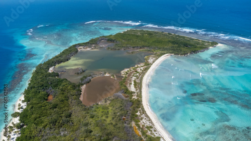 View of a small white sandy key with two lagoons surrounded by a deep blue sea