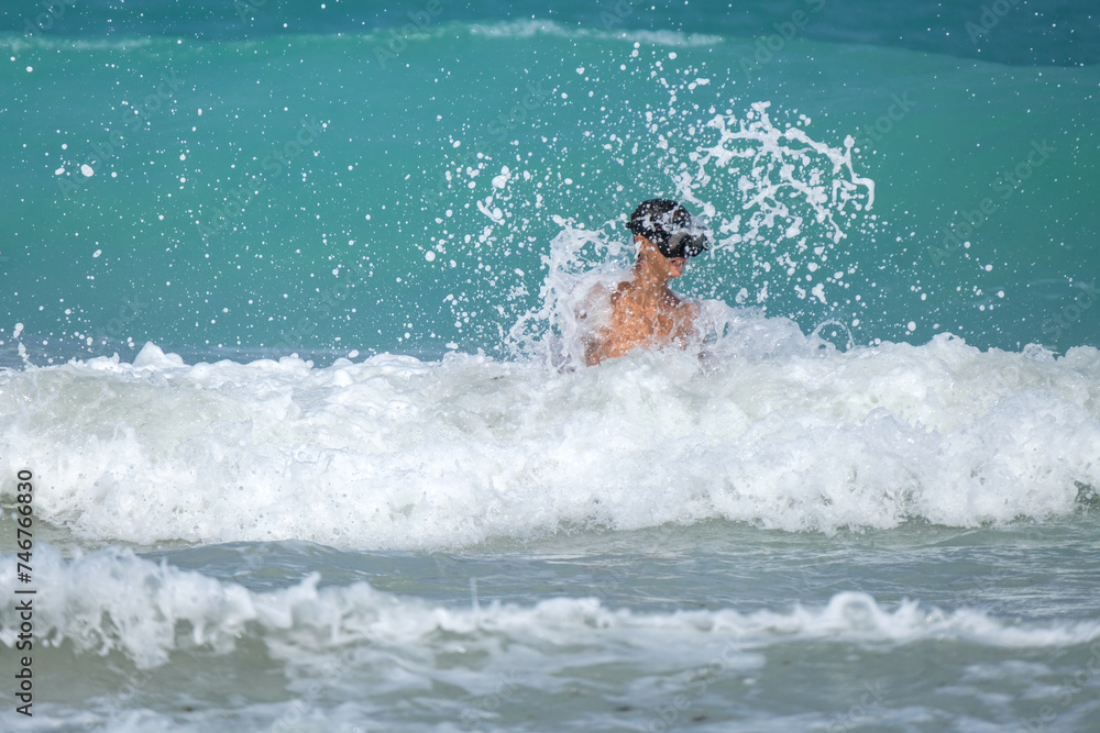 A wave hitting a child in the face in a turquoise sea