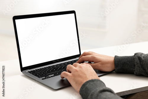 E-learning. Young man using laptop at white table, closeup