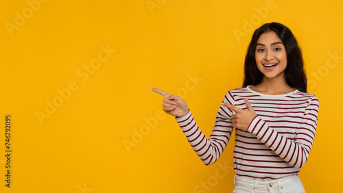 Positive beautiful young indian woman pointing at blank space © Prostock-studio