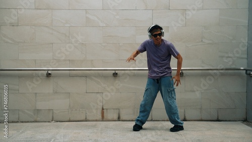 Motion shot of hipster listen music while move or dance to music at dancing room. Attractive street dancer practice b-boy footstep. Freestyle dance concept. Lifestyle. Outdoor sport 2024. Sprightly.