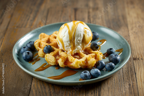 plate of belgian waffle with caramel sauce and blueberries