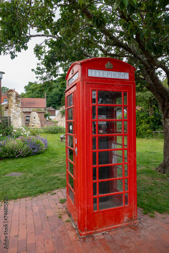 An iconic red telephone box among lush greenery of an English countryside garden