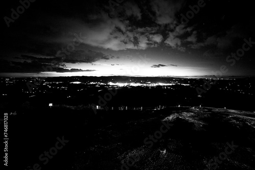 Paisagem em preto e branco de cidade e céu carregado de nuvens durante a noite.  photo