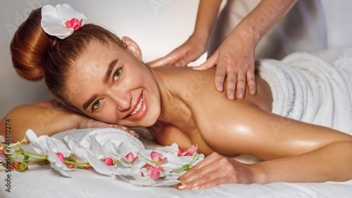 Woman enjoying back massage, smiling at camera