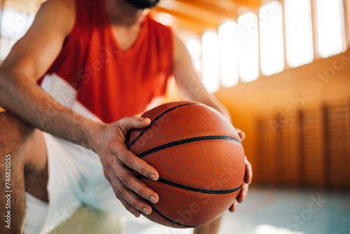 Close up of basketball player's hands holding a ball on court.
