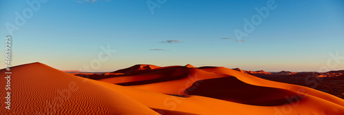 Sunset in the Sahara desert. The sun illuminates the dunes red. Without any human traces. Merzouga, Morocco