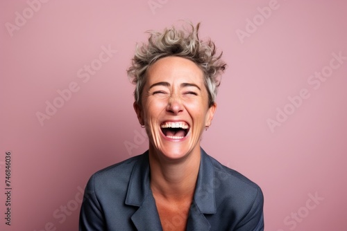 Portrait of a happy business woman laughing on a pink background. © Inigo