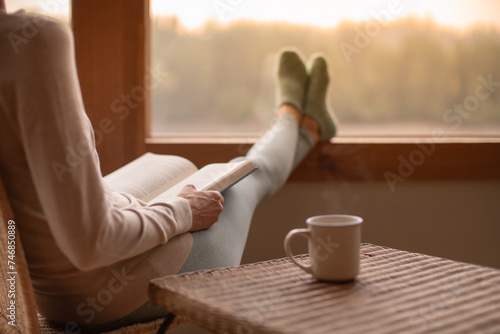 Woman Person relaxing at home reading book feeling relaxed on a cozy winter morning enjoying cup of hot tea coffee
 photo