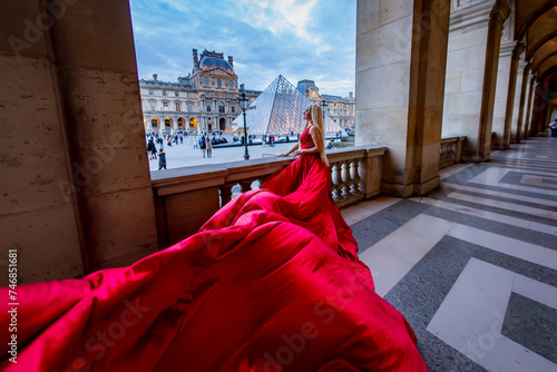 Beautiful pretty blonde woman in red long dress in Paris, France. Eiffel Tower, Louvre,  Galeries LaFayette background. Fashion tourist travel concept.