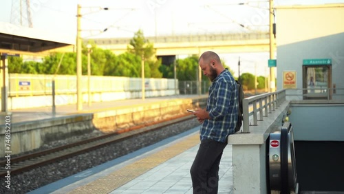 Young adult playing video games or watching social media content while heading to work office in public transport, subway, suburb commuter train. Technology in daily life addiction to digital gadget photo