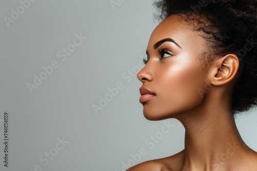 Young multiracial calm female models with exposed shoulders and flawless complexion seen from the side against a light gray backdrop © VolumeThings