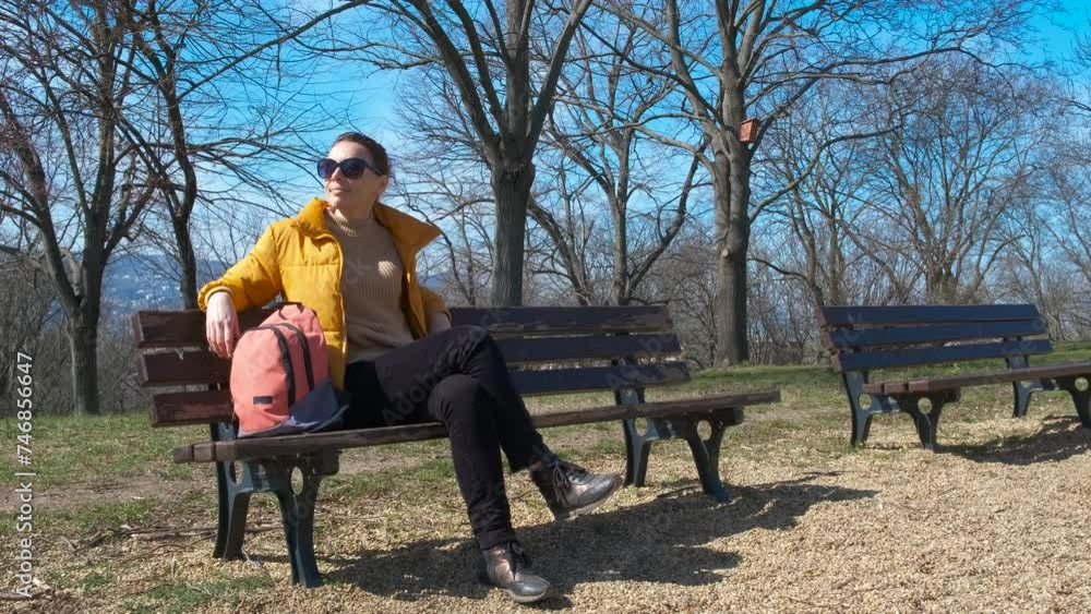 Resting lady tourist on park bench. A view of smiling resting woman on sunny park bench with backpack. Resting lady tourist on park bench. A view of smiling resting woman on sunny park bench with backpack.