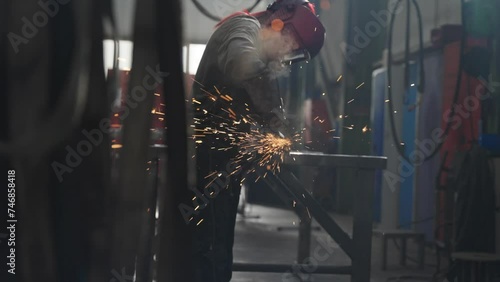 Arbeiterin schleift den Stahl mit dem Winkelschelifer / Flex ab und bereitet ihn für den weiteren Arbeitsvorgang für die Industrie vor. photo