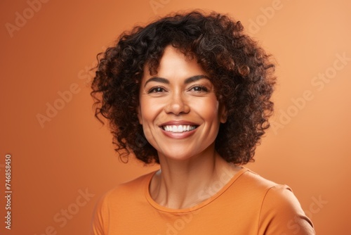 Portrait of smiling african american woman on orange background. © Inigo