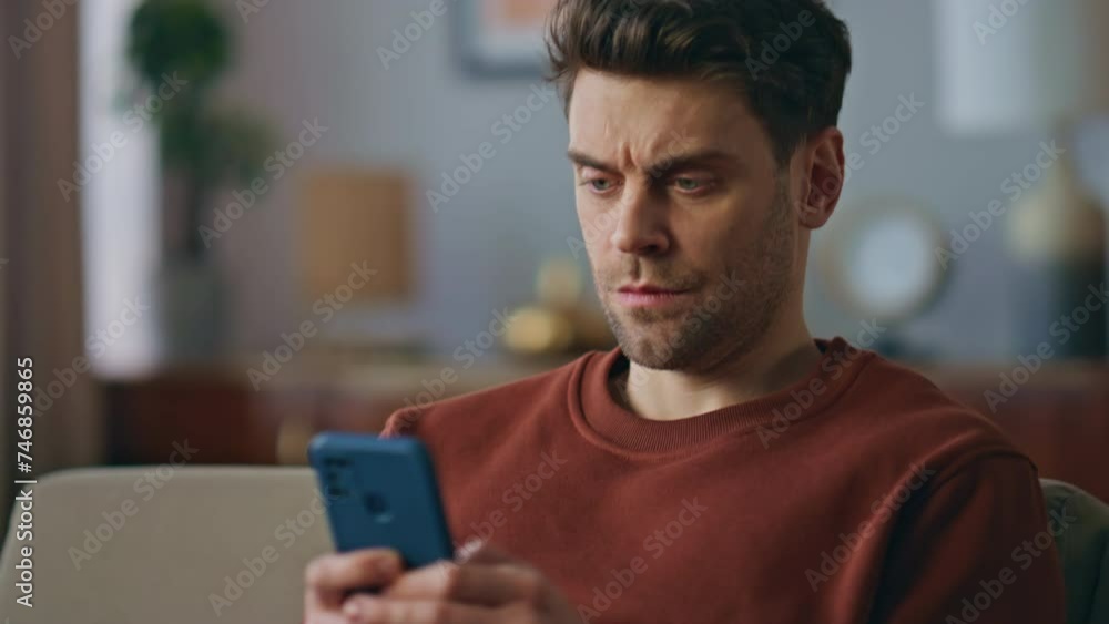 Worried guy texting message on smartphone at sofa close up. Tensed man messaging Worried guy texting message on smartphone at sofa close up. Tensed man messaging