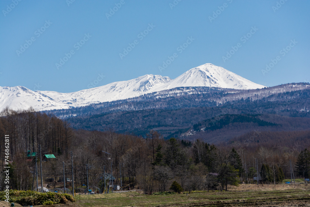 春の晴れた日の水田地帯と冠雪の山並み　大雪山
