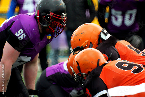 American football players in orange uniforms against players in purple uniforms 