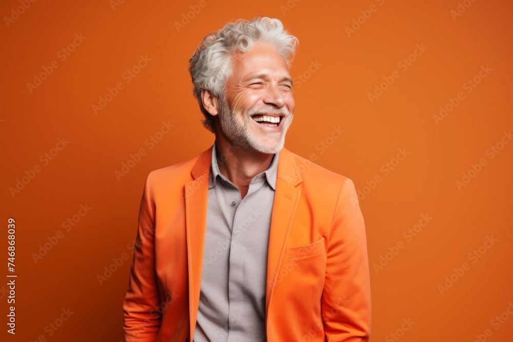 Cheerful senior man laughing and looking at camera on orange background Cheerful senior man laughing and looking at camera on orange background
