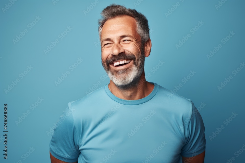 Portrait of smiling mature man in blue t-shirt on blue background Portrait of smiling mature man in blue t-shirt on blue background
