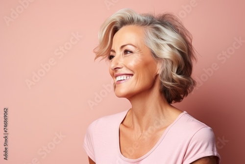 Portrait of a happy senior woman smiling at the camera over pink background