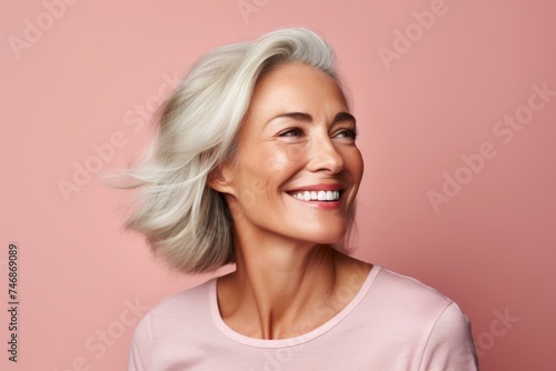 Portrait of smiling senior woman with white hair looking away over pink background