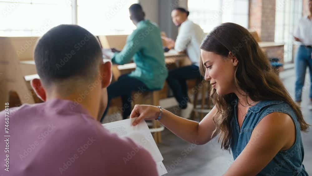 Male and female businesspeople meeting in office discussing document with colleagues working in background - shot in slow motion Male and female businesspeople meeting in office discussing document with colleagues working in background - shot in slow motion