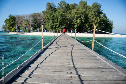 Long wooden pier (bridge) extents from beach at karang panambungan Island photo