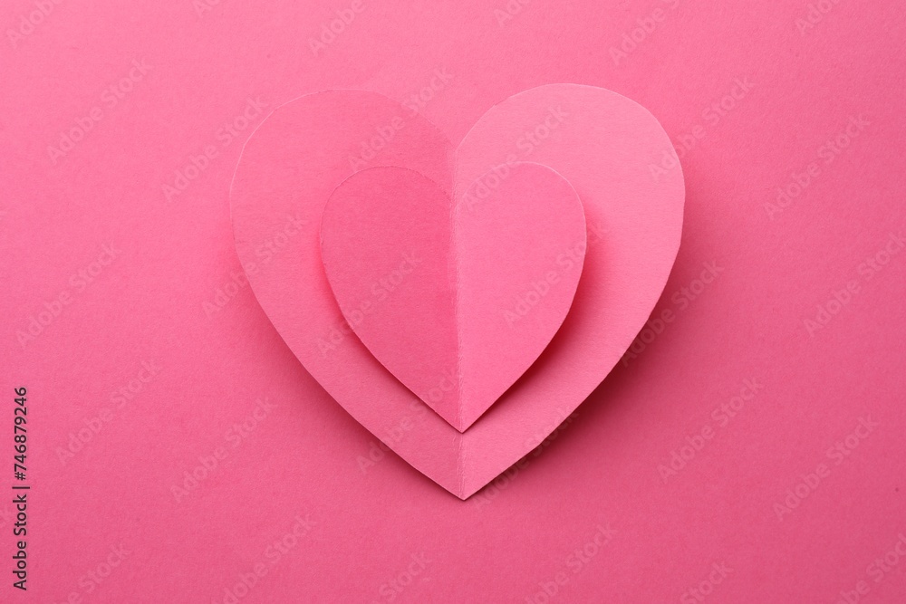 Paper hearts on pink background, top view