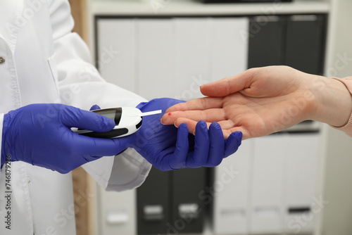 Diabetes. Doctor checking patient's blood sugar level with glucometer in clinic, closeup