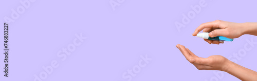 Woman applying sanitizer on her hands against lilac background with space for text