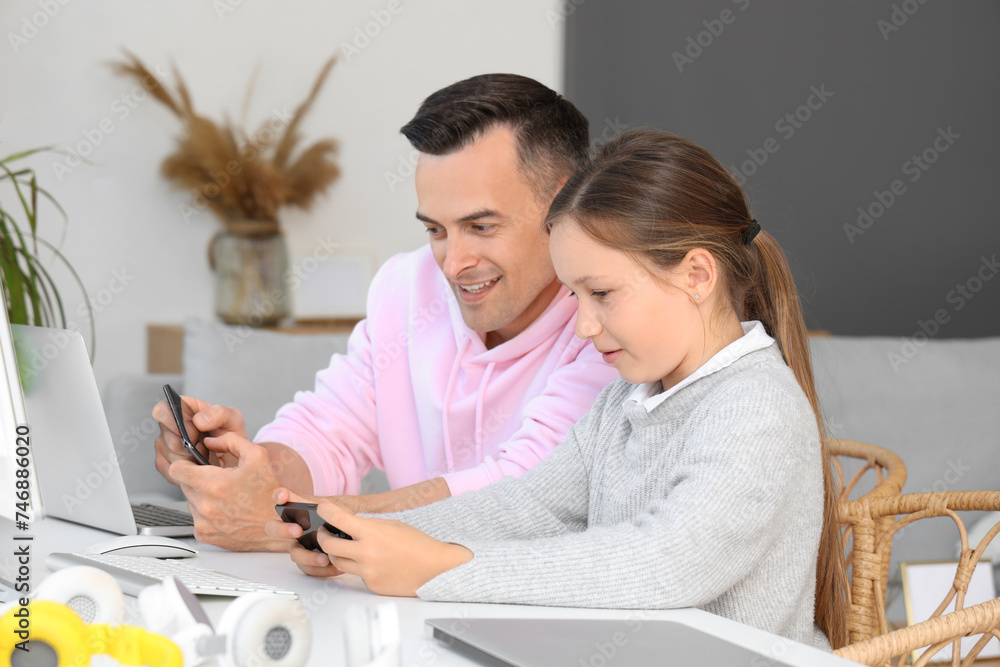Father and daughter sitting at table with computer in living room Father and daughter sitting at table with computer in living room