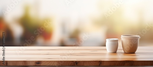 Two ceramic cups are placed on a wooden tabletop in a Scandinavian style kitchen. The table is positioned in front of a window  with natural lighting illuminating the scene.