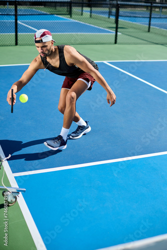 A man in a hat plays pickleball on a blue court