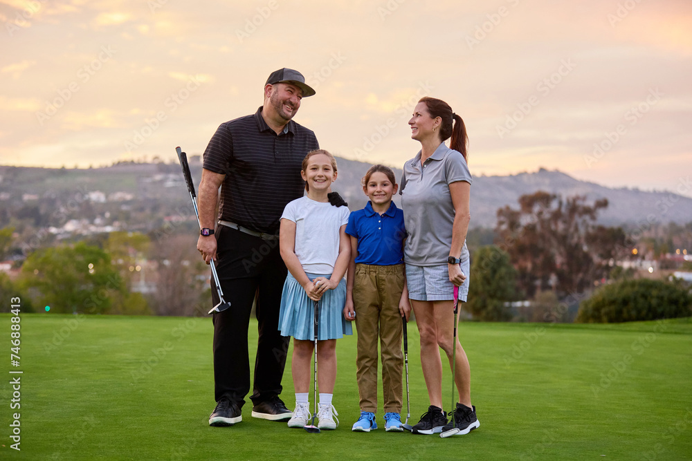 A family poses for a photo on a golf course at dusk