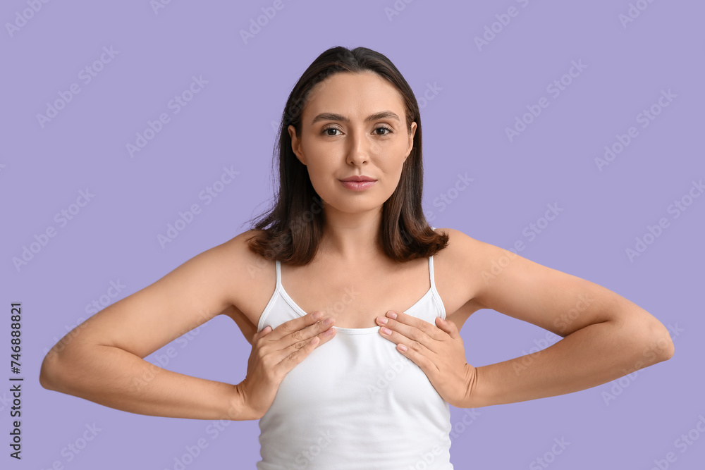 Young woman checking her breast on lilac background. Cancer awareness concept Young woman checking her breast on lilac background. Cancer awareness concept