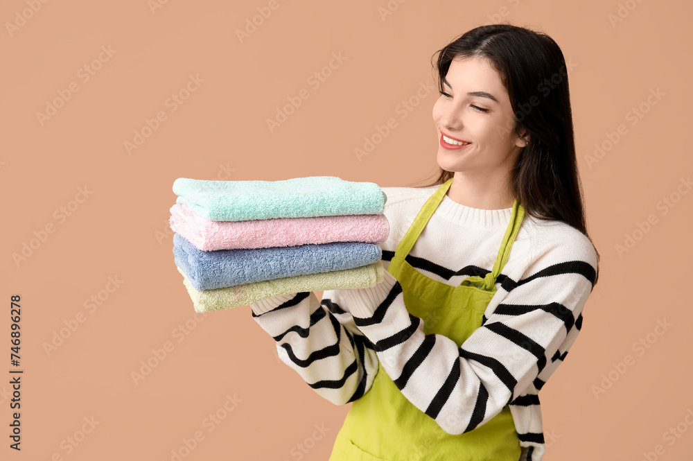 Beautiful young woman with clean towels on brown background