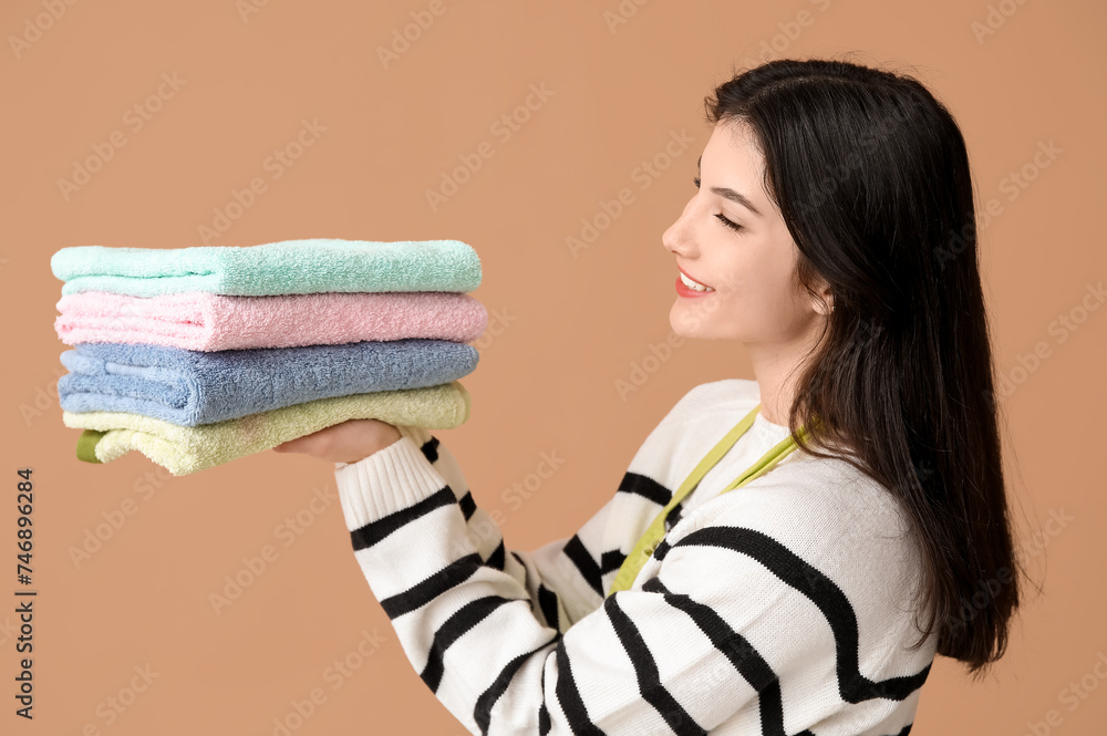 Beautiful young woman with clean towels on brown background Beautiful young woman with clean towels on brown background