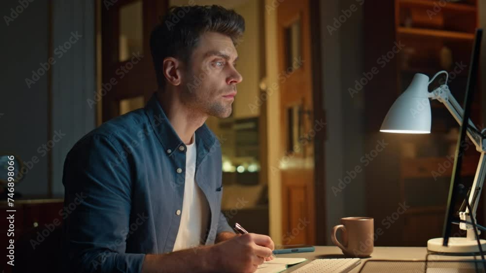 Online man studying pc night home looking screen closeup. Student making notes Online man studying pc night home looking screen closeup. Student making notes