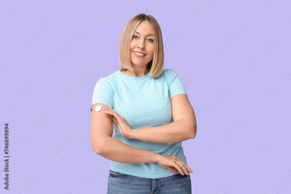 Woman with glucose sensor for measuring blood sugar level on lilac background. Diabetes concept Woman with glucose sensor for measuring blood sugar level on lilac background. Diabetes concept